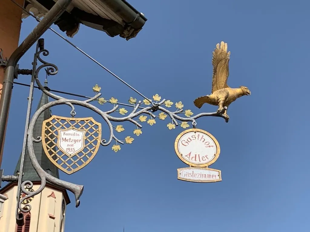 Das schmiedeeiserne Wirtshausschild mit goldenem Adler und dem Wappen der Familie Metzger